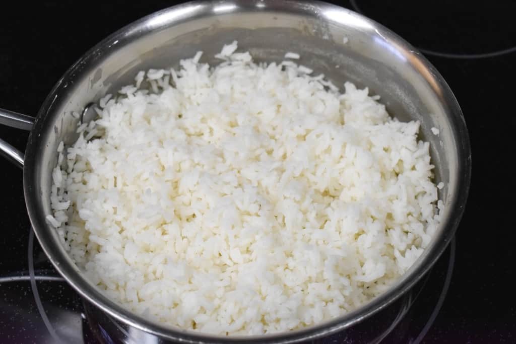 Cooked white rice after it was fluffed with a fork, still in a saucepan.