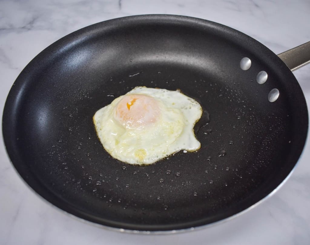 An over-easy fried egg still in a non-stick skillet.
