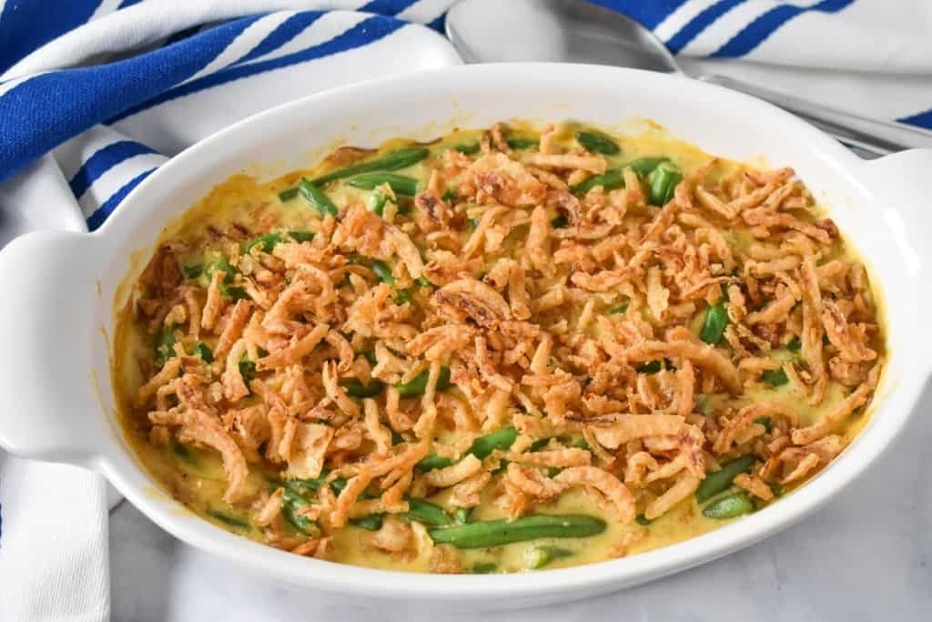 An image of the baked casserole on a white table with a blue and white striped towel in the background.