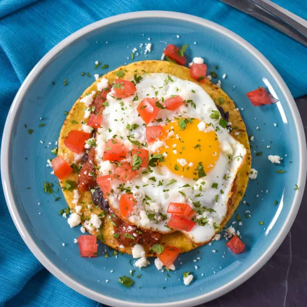 An image of the huevos rancheros set on an aqua plate and linen.