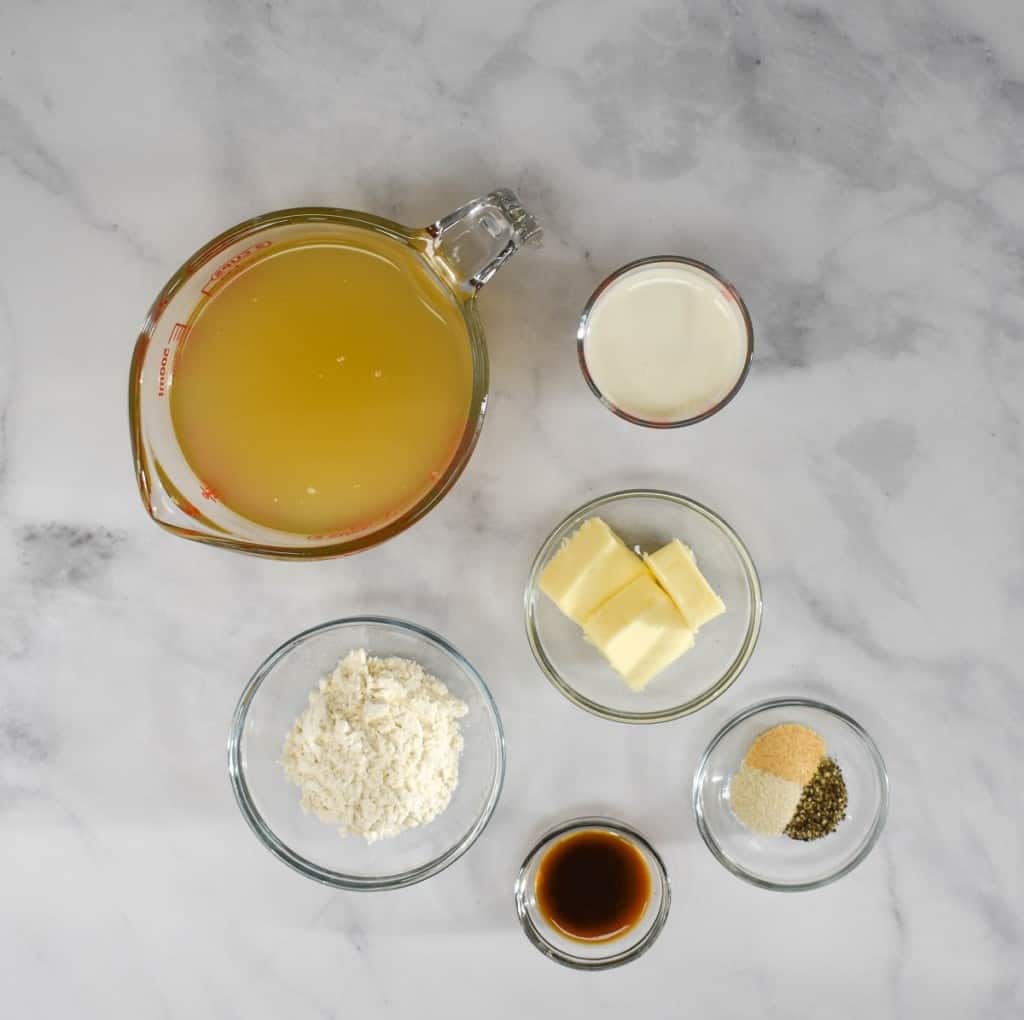 The ingredients for the gravy, prepped and arranged in glass bowls on a white table.