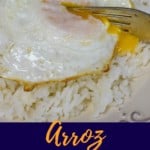 A close up of the arroz con huevo frito with a fork cutting into the yolk and served with sweet plantains. Under the picture there is a blue graphic with the title in aqua and yellow letters.