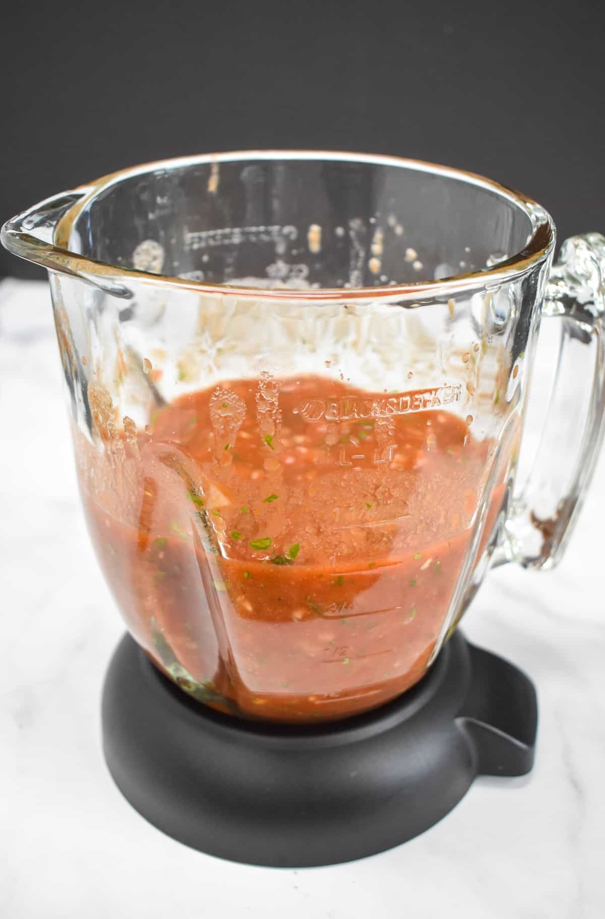 An image of the salsa still in the blender after being processed. The blender is set on a white table.