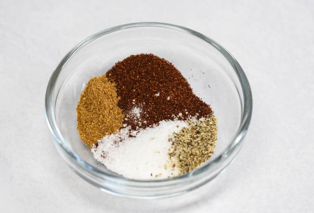 The seasoning for the recipe in a glass bowl set on a white table.