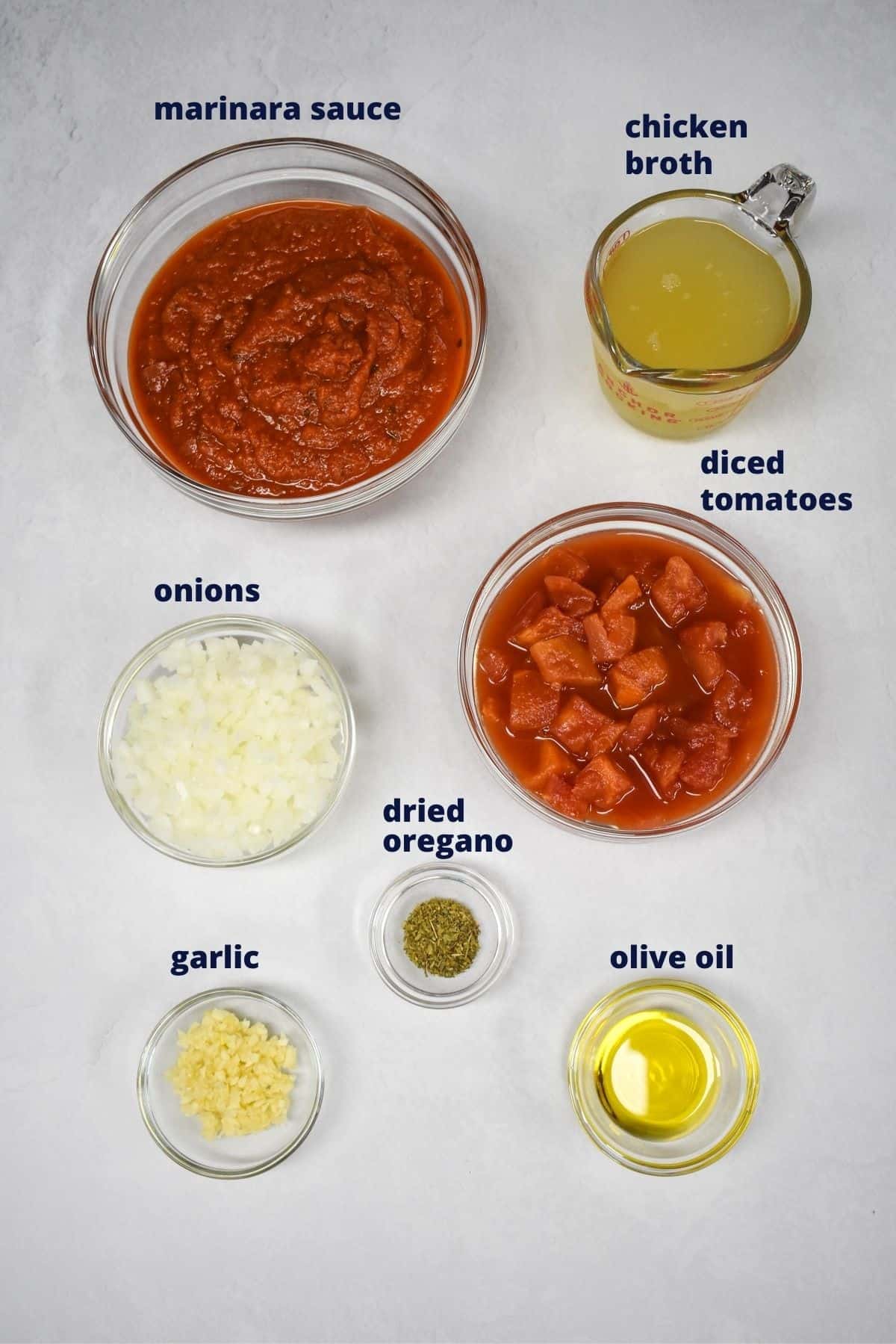 The ingredients for the sauce, prepped and arranged in glass bowls on a white table.