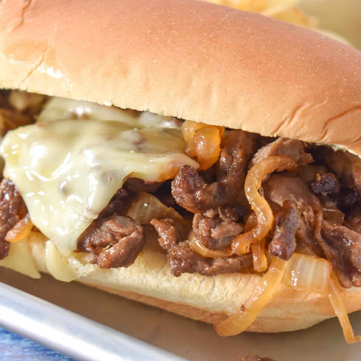 A close up of a steak sandwich on a sheet pan.