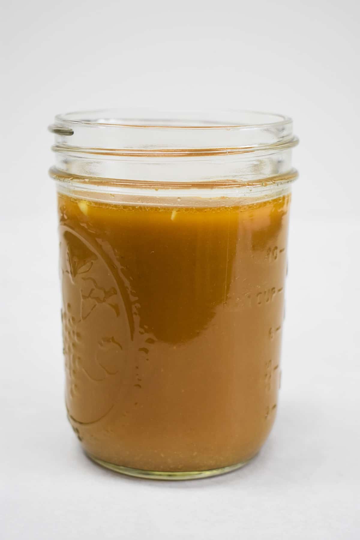 An image of the sauce for the cashew chicken in a mason jar, set on a white table.