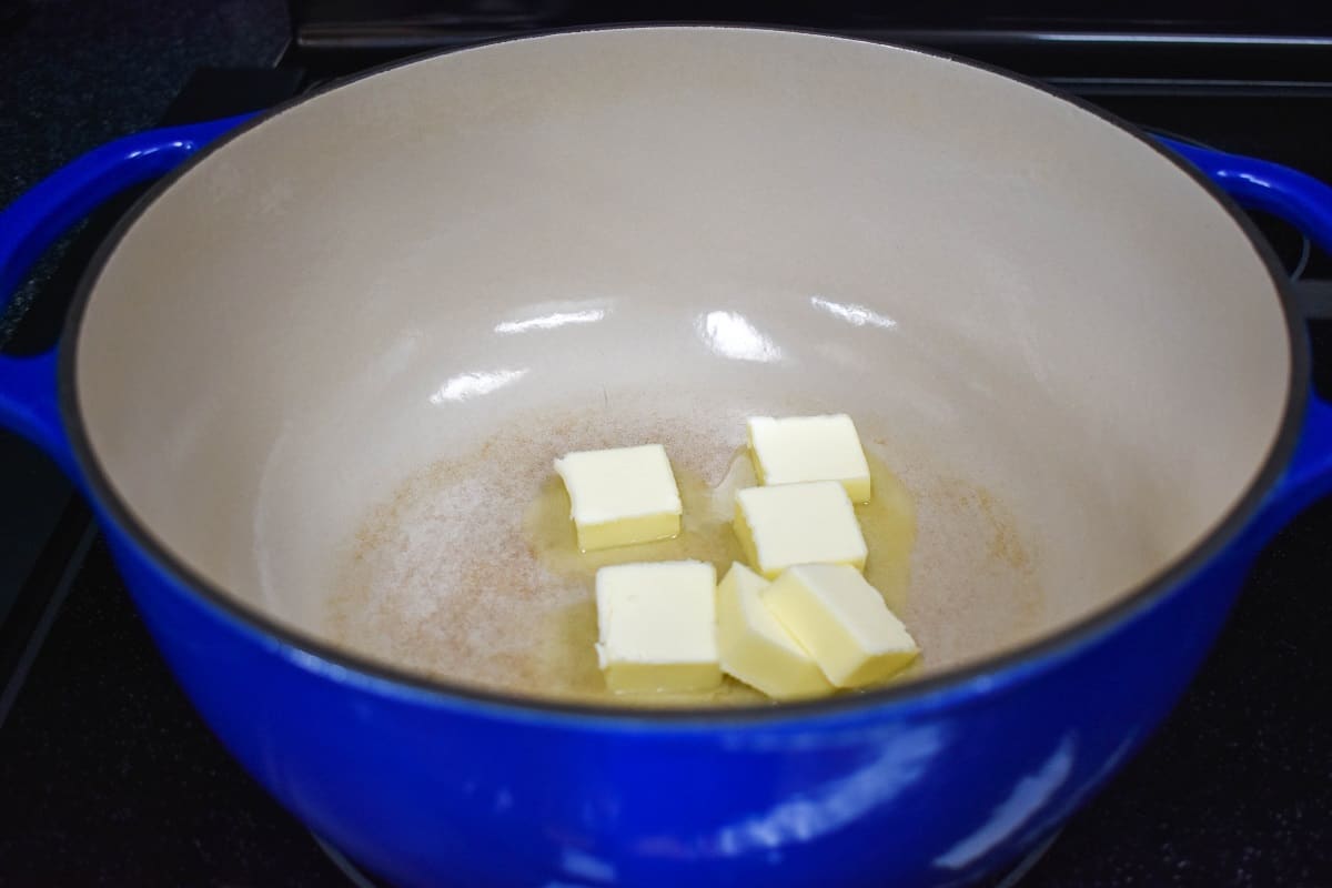 Pats of butter melting in a white and blue pot.