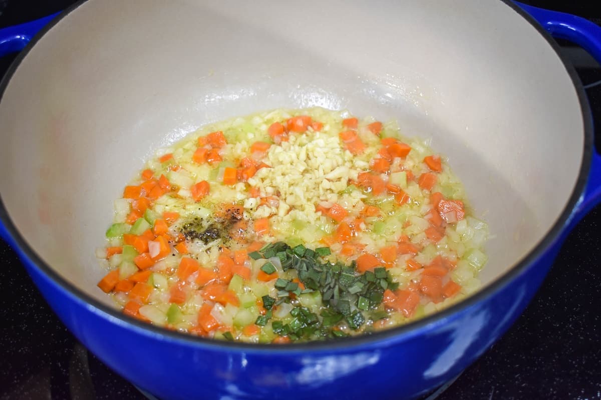 Minced garlic, herbs and spices added to the vegetables cooking in the pot.