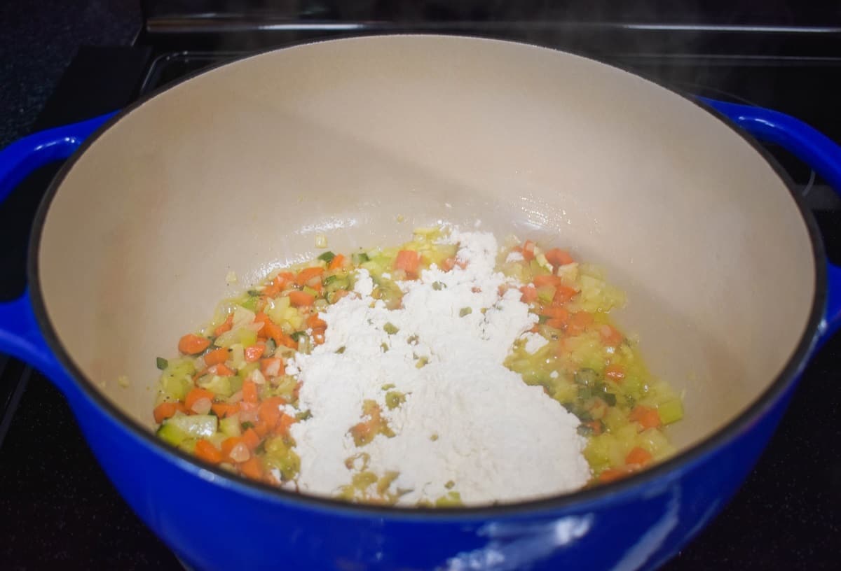 Flour added to the vegetables cooking in the pot.