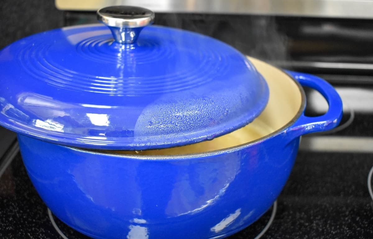 A large blue pot half covered on a stove.