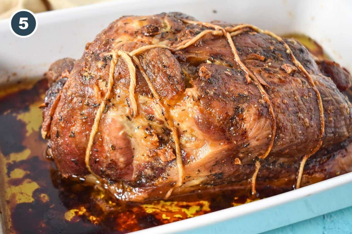 Fully roasted pork shoulder in baking dish, browned and crusty.