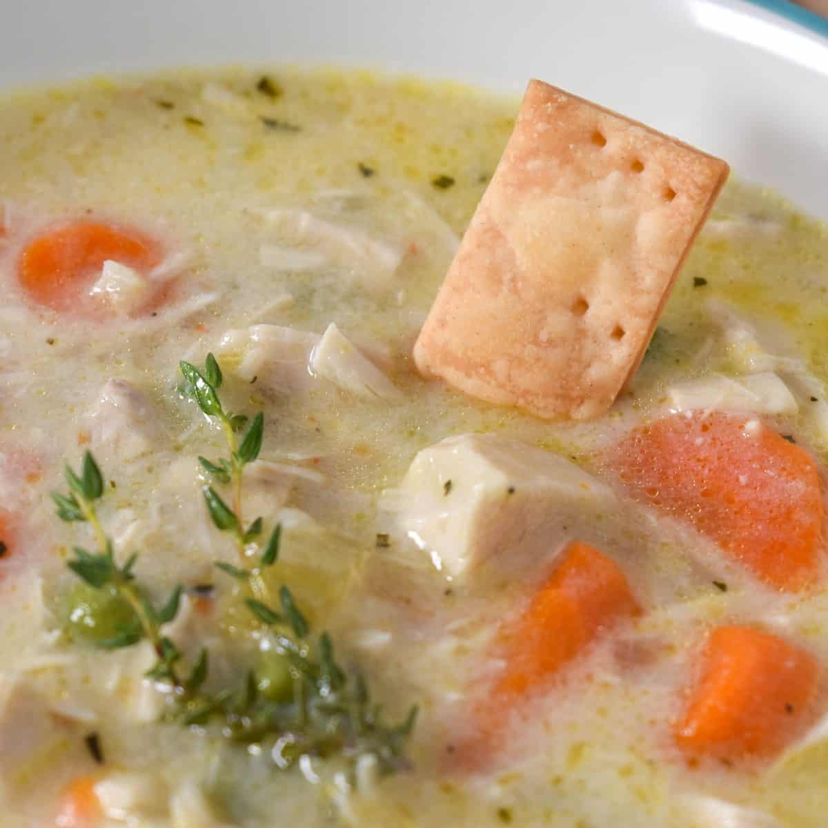 A close up image of the soup with a small pie crust cracker dipped in it.