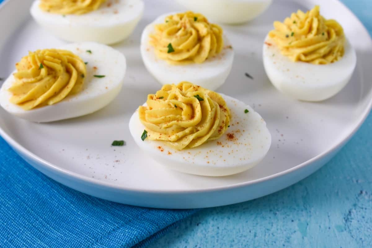 A close up image of the finished eggs garnished and served on a white plate. The plate is set on an aqua table.