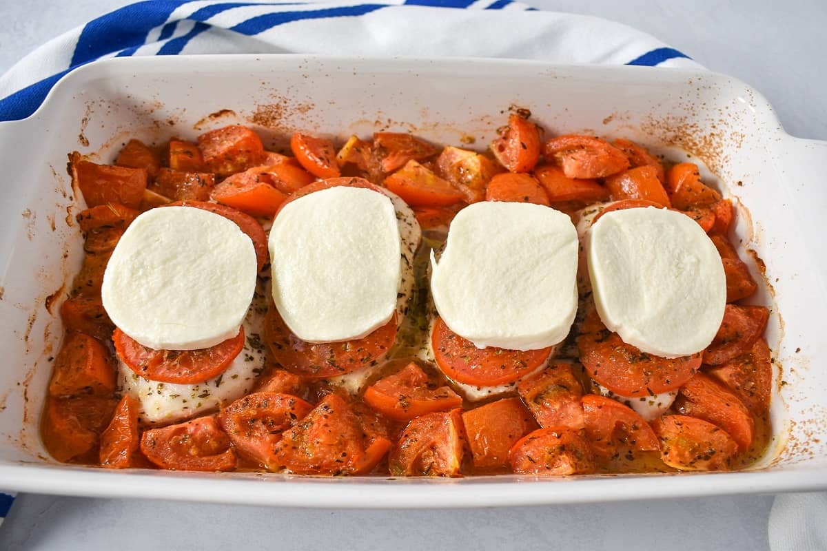 The baked chicken and tomatoes topped with thick slices of mozzarella cheese.