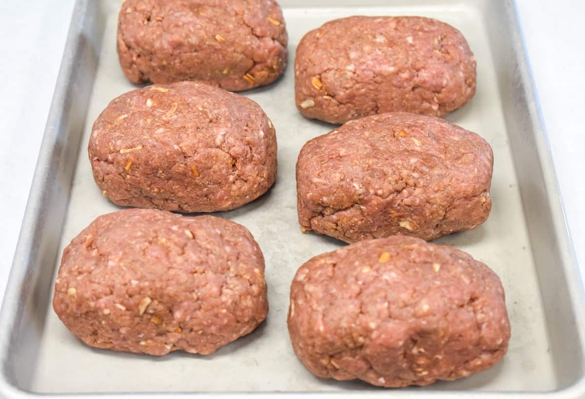 An image of six formed loaves set on a baking sheet.