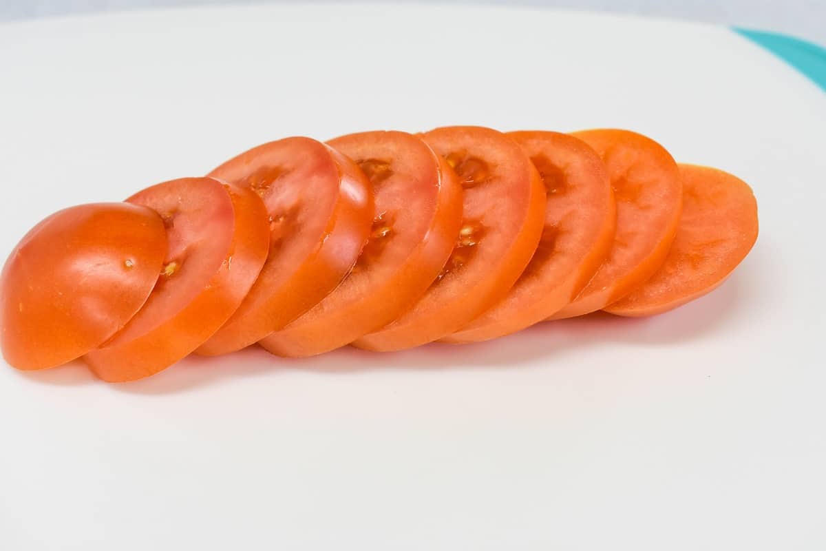 Sliced tomatoes on a white cutting board.