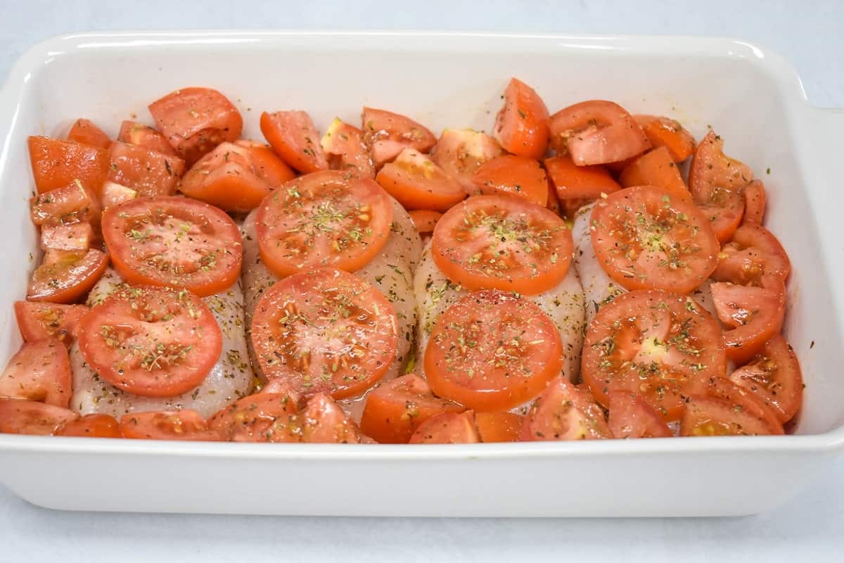 The prepared caprese chicken in a white baking dish, before baking.