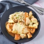 The French onion chicken served with brown rice on a black plate.