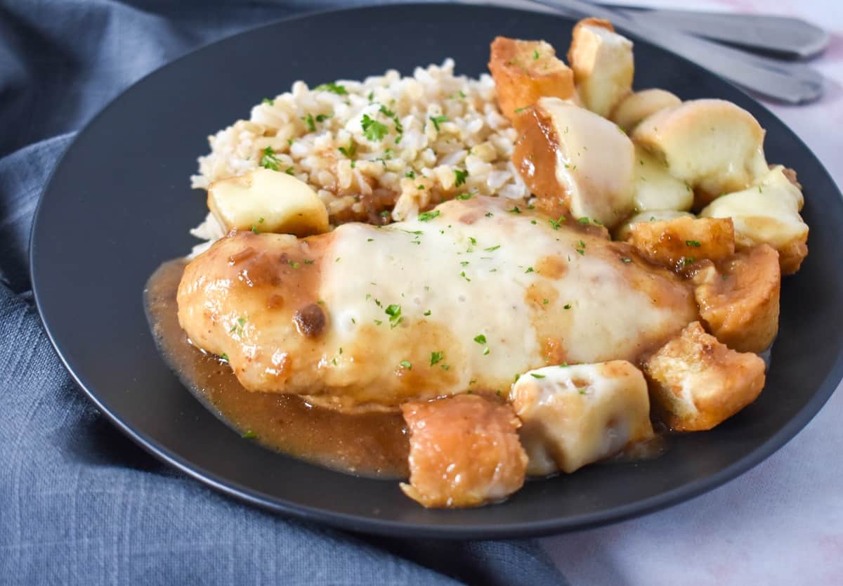 A close up image served with white rice on a black plate.