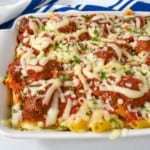 An image of the baked pasta with meatballs in a white casserole dish with a blue and white kitchen towel in the background.