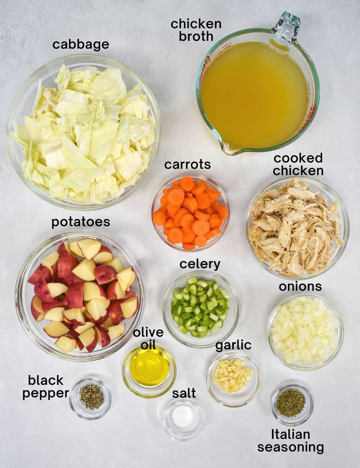 The ingredients for the soup arranged in glass bowls on a white table.