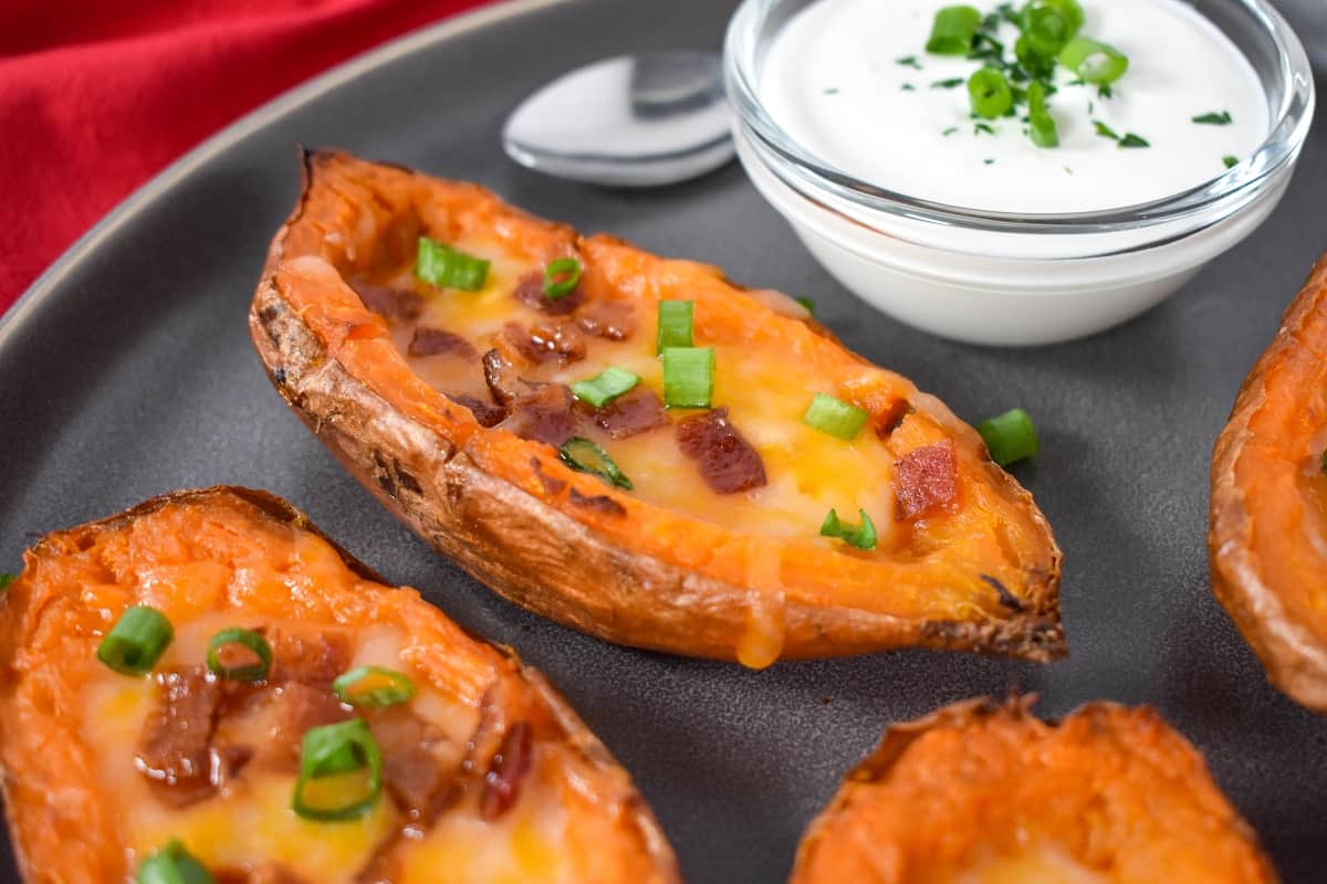 A close-up image of the sweet potato skins on a gray plate with a side of sour cream.