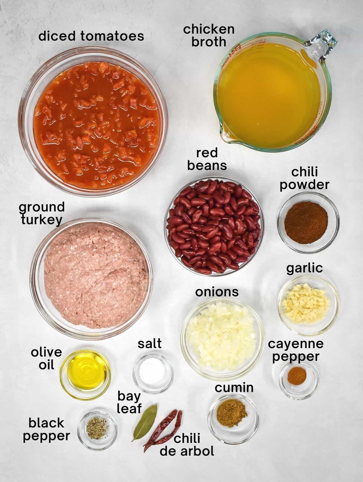 The ingredients for the chili, prepped and arranged in clear bowls on a white table.