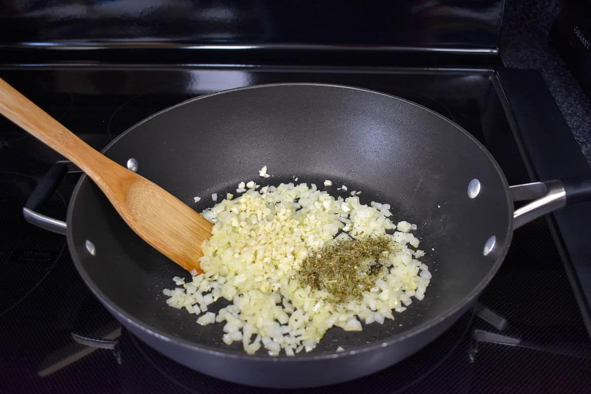 Garlic and Italian seasoning added to the sautéed onions in a large skillet.