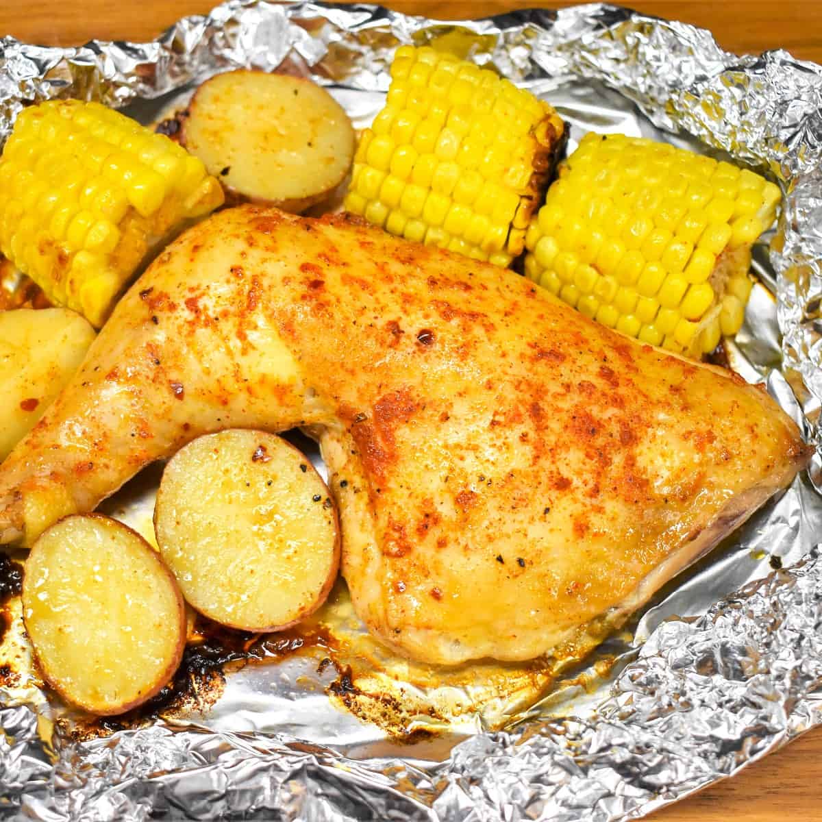 An image of the chicken, potatoes, and corn in an open foil pack.