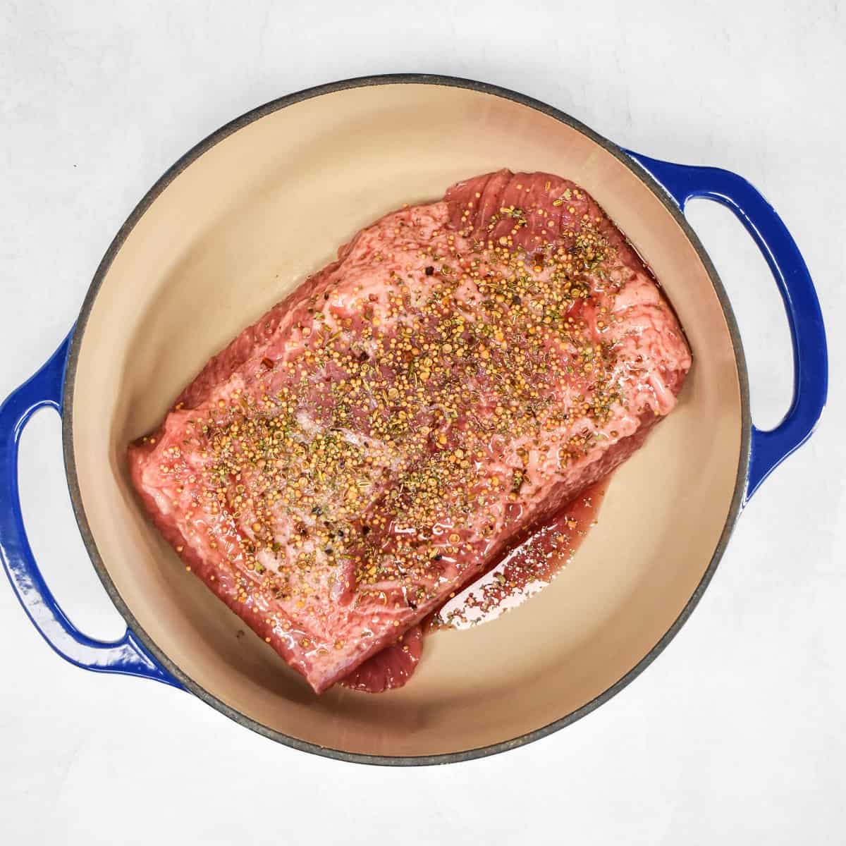 An image of the beef in a large pot and the top is covered with the seasoning mix.