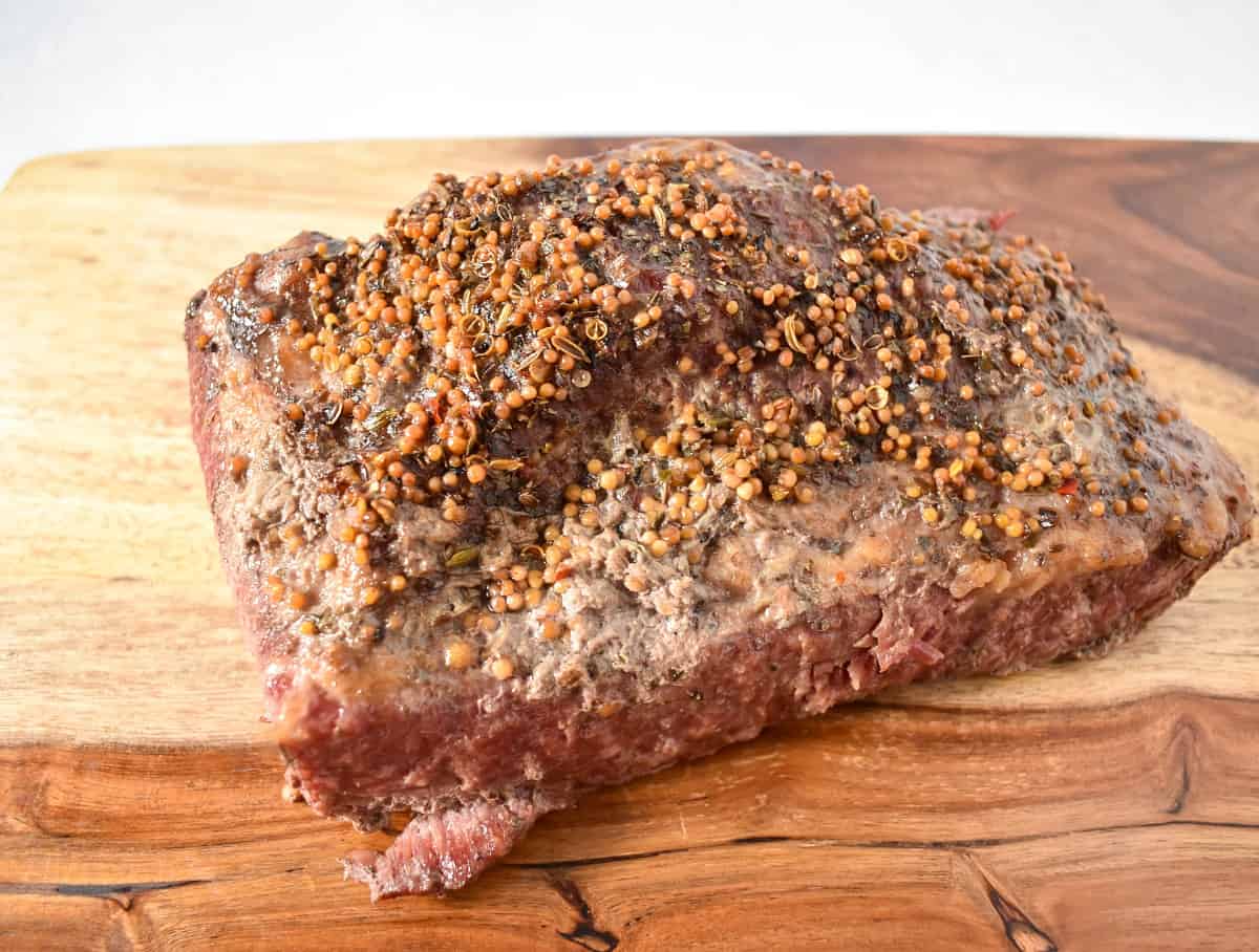 An image of the cooked corned beef before slicing, set on a wood cutting board.