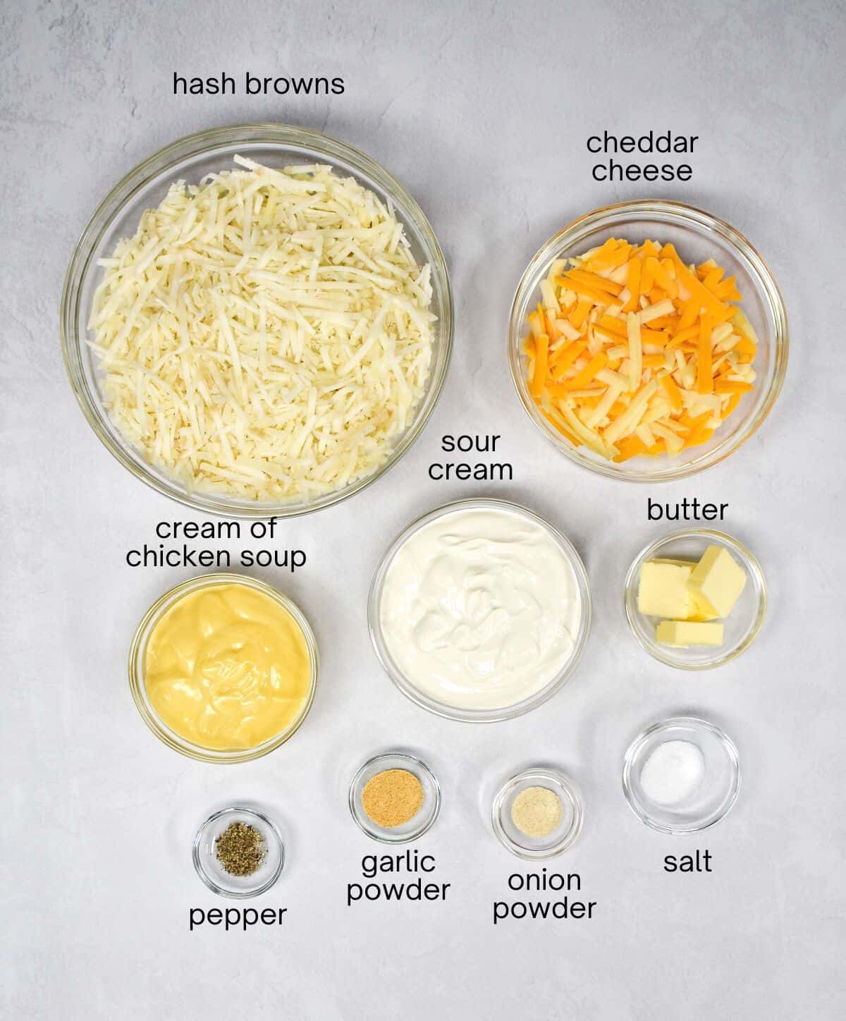 The ingredients for the casserole arranged in glass bowls and set on a white table. Each ingredient has the title in small, black letters.
