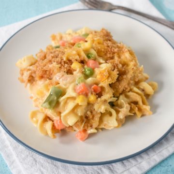 A serving of chicken noodle casserole on a white plate set on a white linen.