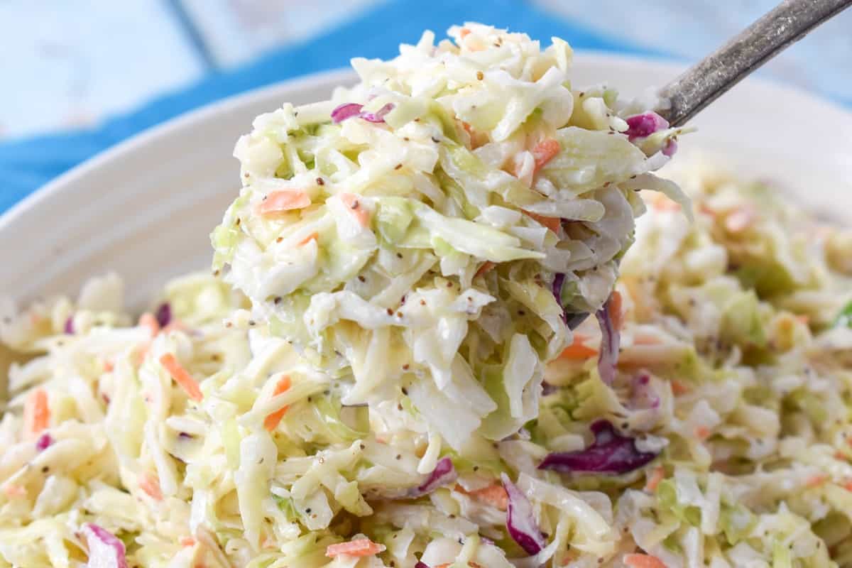 An image of a large spoonful of the finished slaw held up over the serving dish.