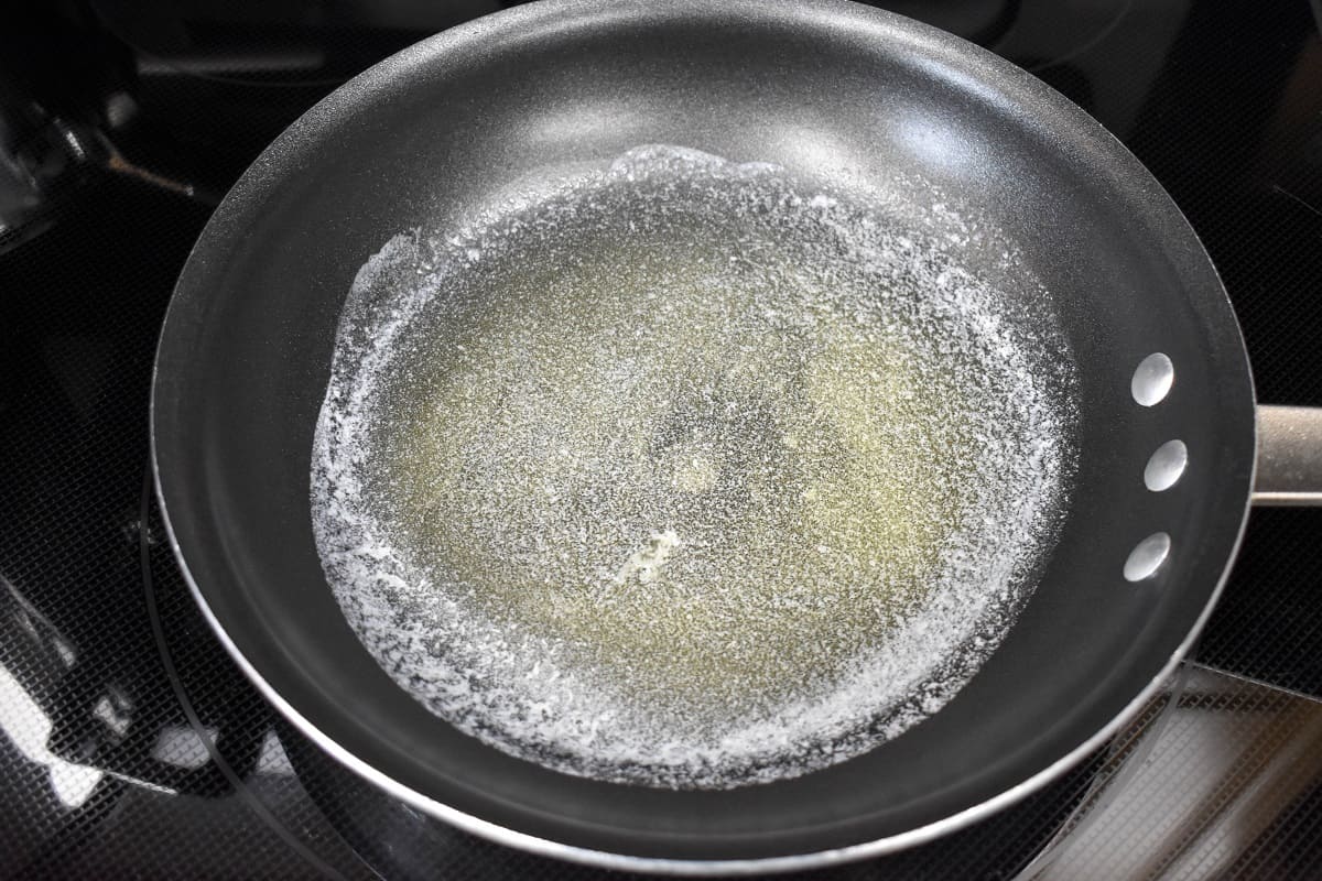 An image of butter melted in a non-stick skillet.