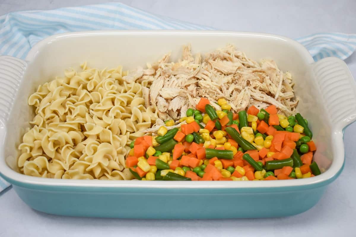 An image of the egg noodles, shredded chicken and mixed vegetables in a large baking dish.