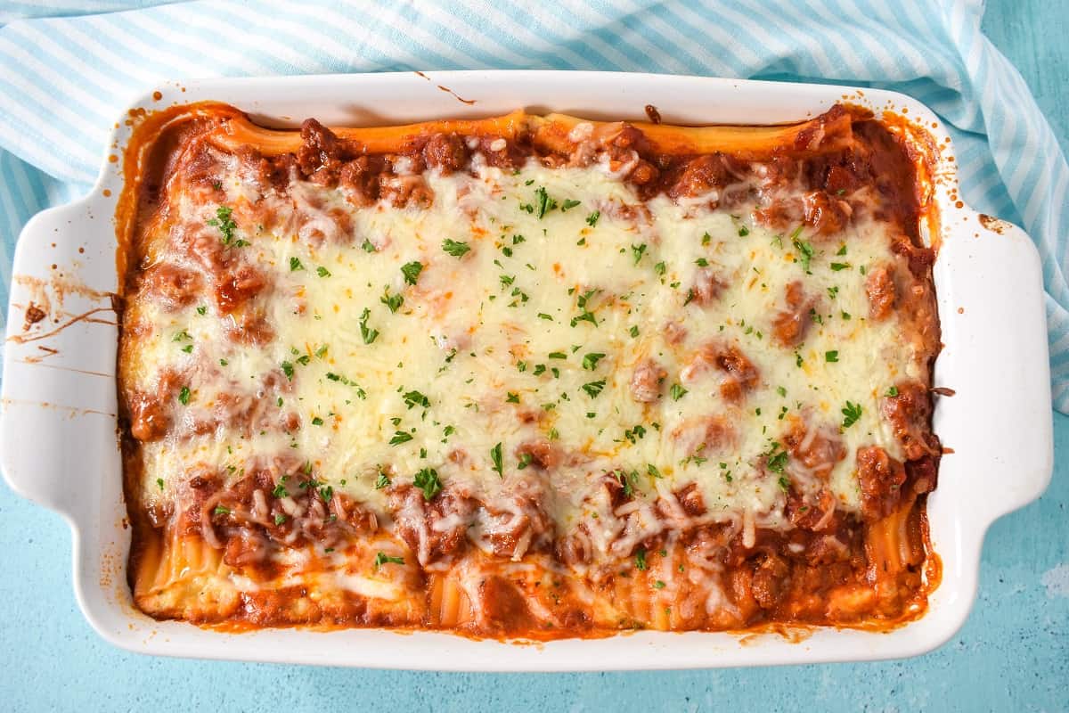 An image of the baked manicotti set on a light blue table.