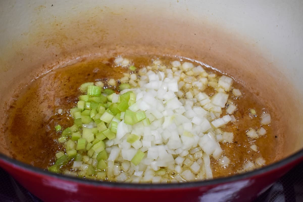 An image of diced onions and celery sautéing in a large pot.