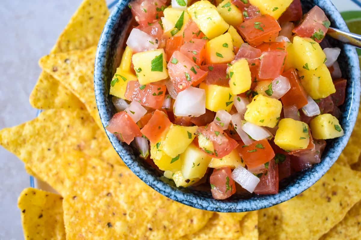 A close-up image of the mango salsa served in a bowl surrounded by tortilla chips.