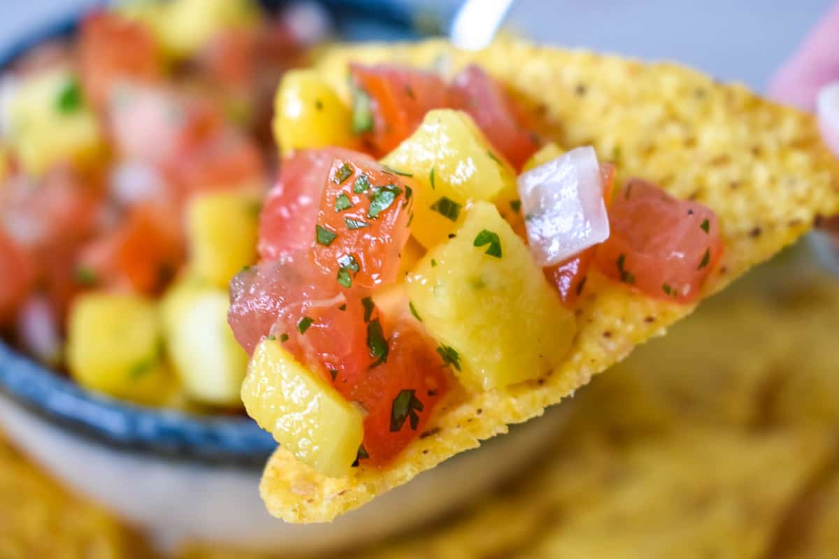 A close-up image of a scoopful of salsa held up by a tortilla chip.