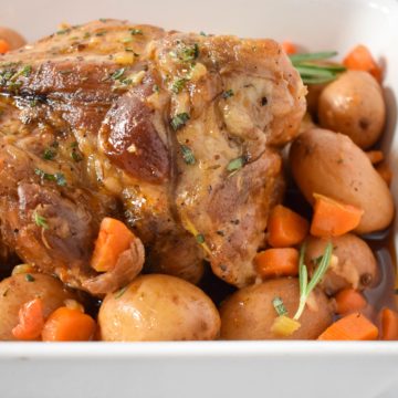 An image of the pork pot roast with the potatoes and carrots in a white dish.