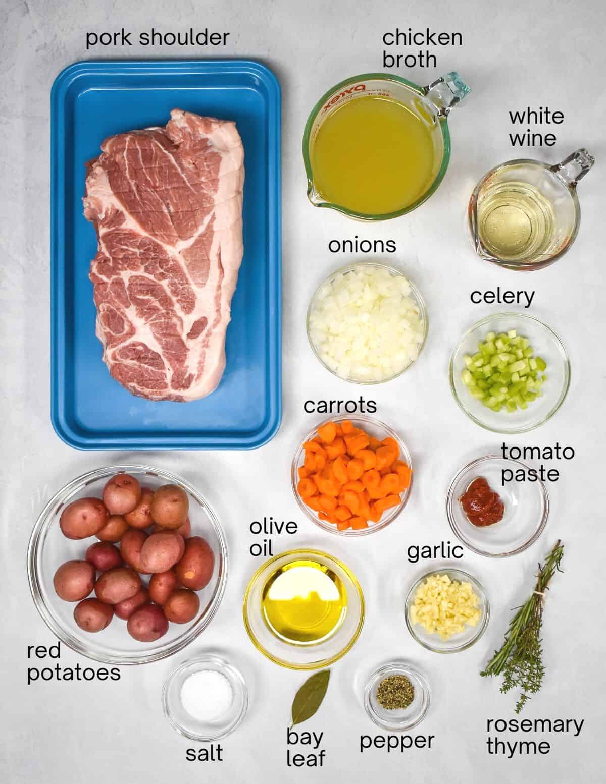 The ingredients for the pot roast arranged on a white table with each labeled in small, black letters.