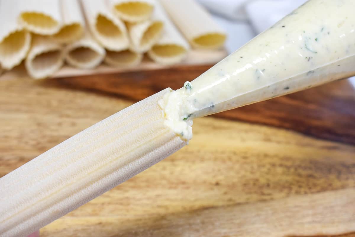 An image of the pasta tube being filled with the cheese mixture.