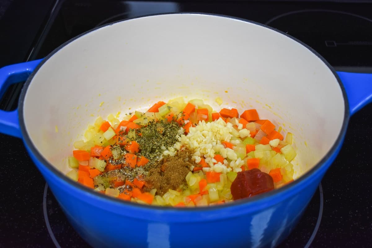 Onions, carrots, celery, garlic, tomato paste, and spices cooking in a large pot.