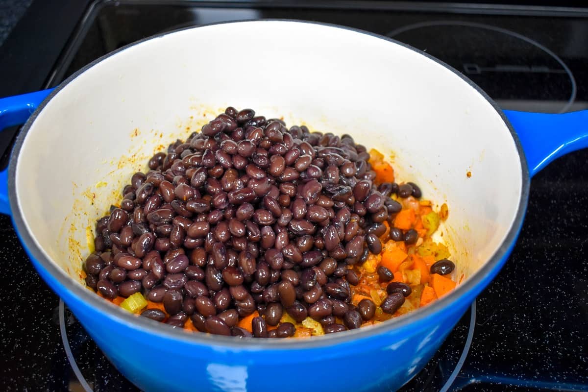 Black beans added to the vegetables in the pot.