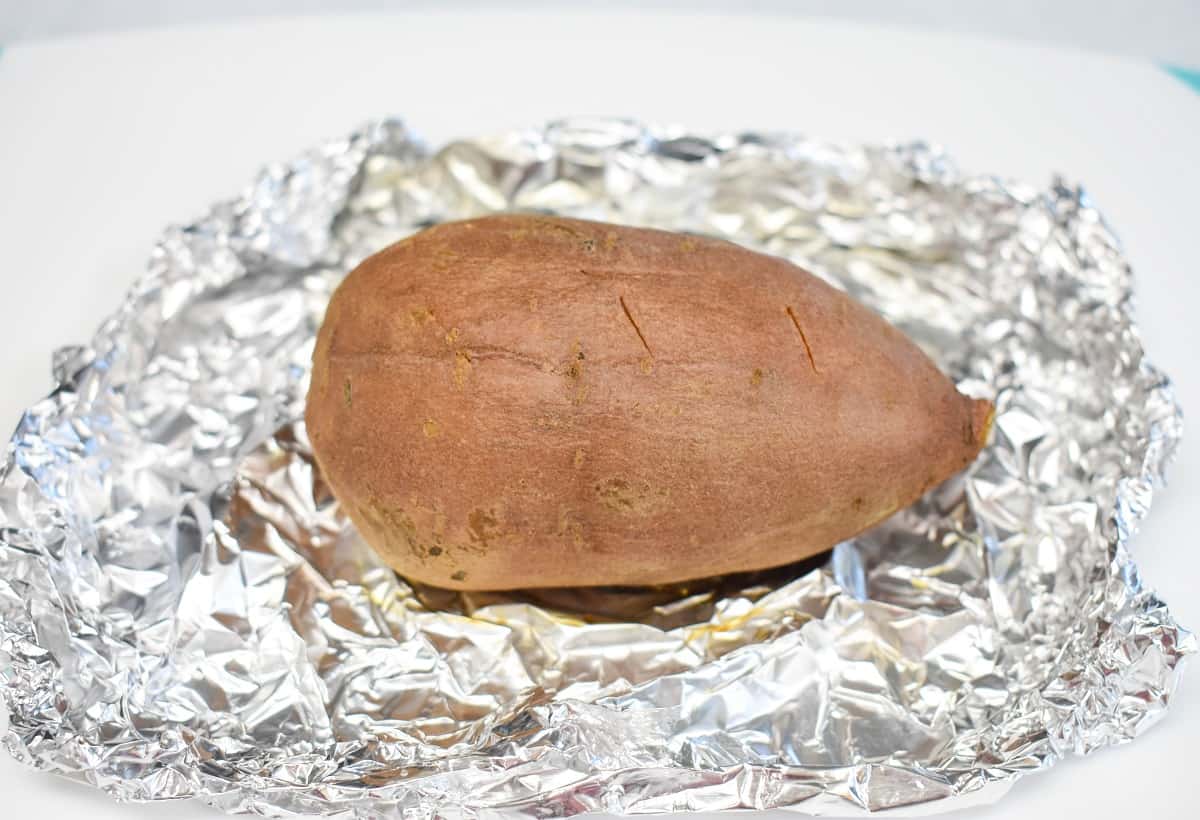 A cooked sweet potato on a crumbled piece of foil.