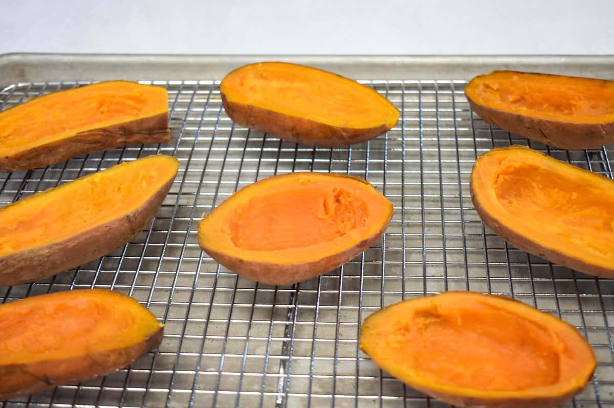 Scooped out potato skins arranged on a baking sheet lined with a cooling rack.6