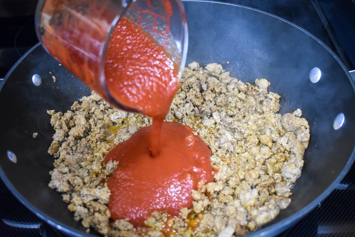 Tomato sauce being added to the browned ground turkey mixture.