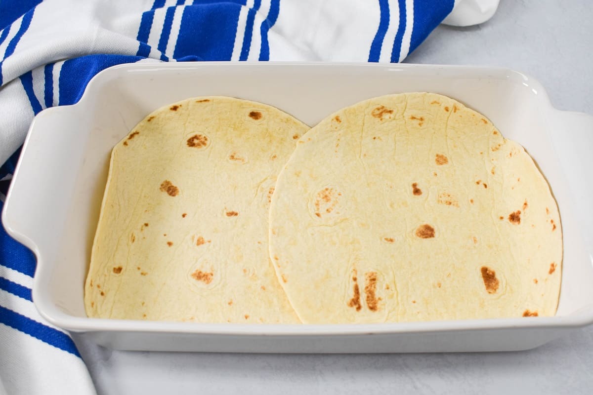 Two flour tortillas lining a white baking dish.